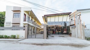 Un bâtiment moderne doté d’une entrée sécurisée par un portail, de nombreux balcons et d’un espace couvert avec une façade en verre.