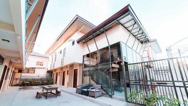 Un bâtiment moderne doté d’une façade en verre, d’un espace extérieur aménagé pour s’asseoir et d’un escalier menant à un niveau supérieur.