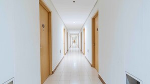 A long, narrow hotel corridor with wooden doors and white walls. - RedDoorz Premium @ SMDC Fairview (Quezon City)