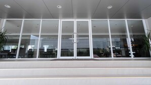 A modern building entrance with large glass doors, a flat roof, and a few potted plants. - RedDoorz Premium @ SMDC Fairview (Quezon City)