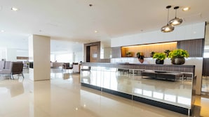 A modern hotel lobby with a central reception desk, seating area, and potted plants. - RedDoorz Premium @ SMDC Fairview (Quezon City)