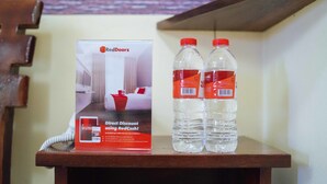 Une enseigne RedDoorz affichant une offre de réduction immédiate, ainsi que deux bouteilles d’eau posées sur une table en bois.