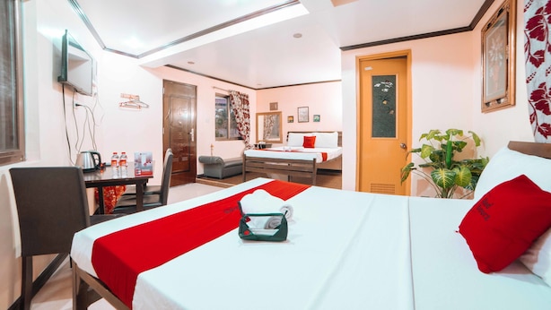 Une chambre d’hôtel équipée d’un lit, d’un bureau, d’une chaise, d’une table avec une bouilloire et d’un téléviseur.