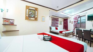 Une chambre d’hôtel avec deux lits, un bureau et une chaise. On y trouve une petite table sur laquelle sont posés une bouteille et un tableau encadré accroché au mur.