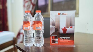 Deux bouteilles d’eau sont posées sur une table, à côté d’un panneau publicitaire de RedDoorz.