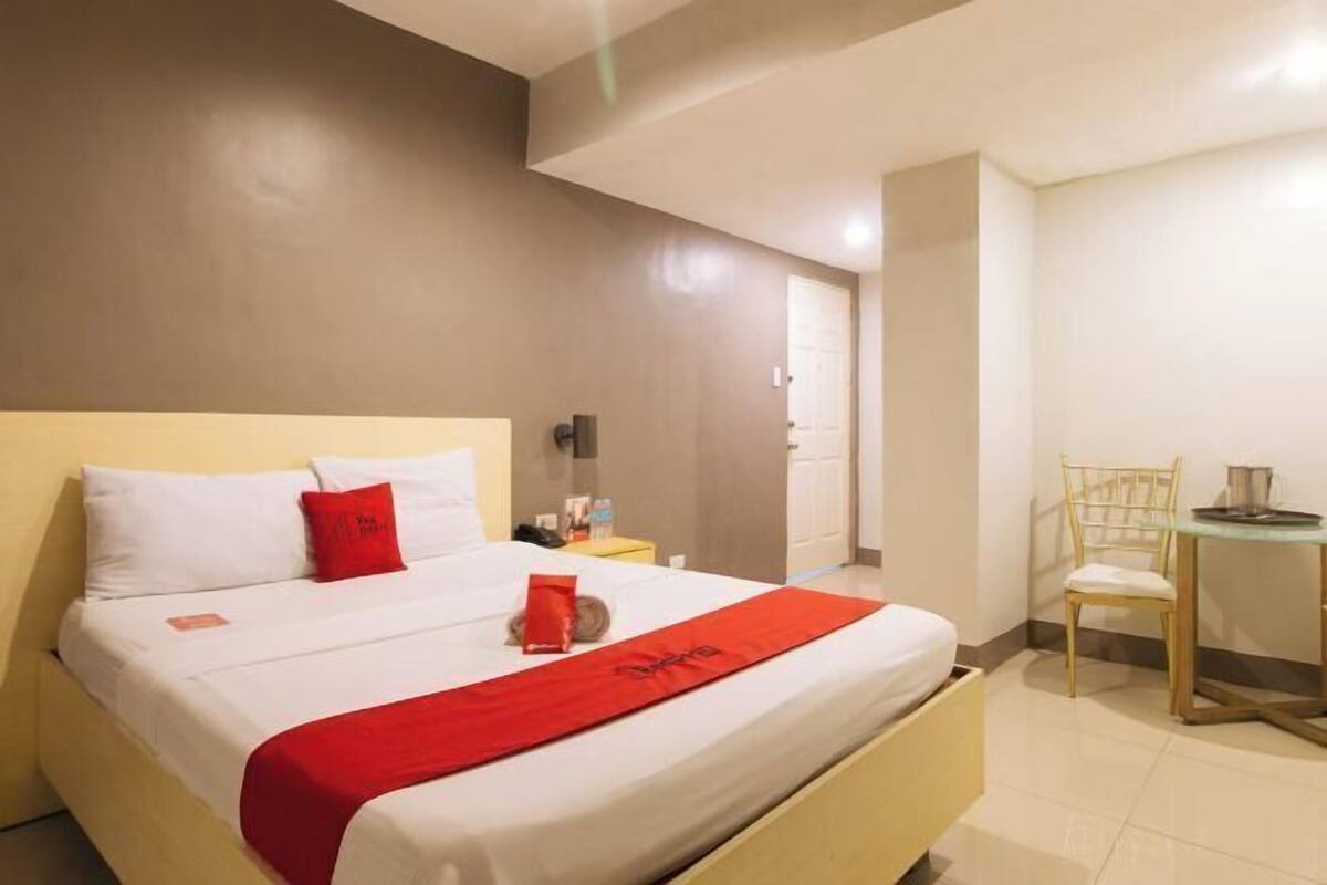 A hotel room with a bed, a desk, and a chair.