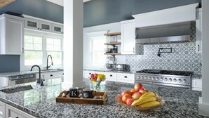 A modern kitchen with granite countertops, white cabinetry, a stainless steel range, and a patterned backsplash. - Keystone Inn Bed and Breakfast (Gettysburg)