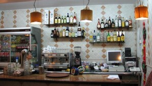 A bar area with shelves of liquor bottles, a coffee machine, and a computer monitor. - Hotel Nacional (Melilla)