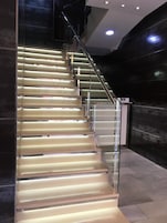 A modern staircase with glass railings and illuminated steps.