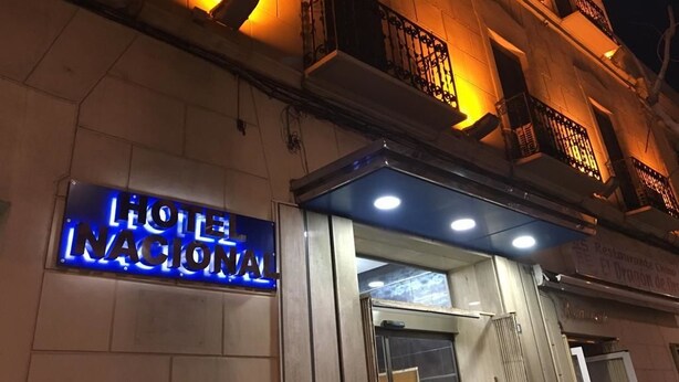 The exterior of Hotel Nacional with illuminated signage and a stone facade. - Hotel Nacional (Melilla)