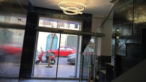 A modern interior with a glass door leading outside, a staircase, and a unique chandelier. - Hotel Nacional (Melilla)