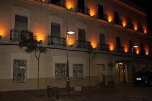 A multi-story building with barred windows and balconies, a street lamp, and a parked car. - Hotel Nacional (Melilla)