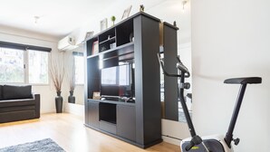 A modern living room with a black entertainment unit, a grey sofa, a standing exercise bike, and a grey rug. - Humboldt 2 by Be Local Argentina (Buenos Aires)