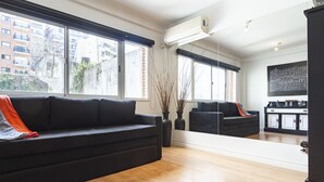 A modern living room with a black sofa, a large mirror reflecting the room, and a view of the city through large windows. - Humboldt 2 by Be Local Argentina (Buenos Aires)