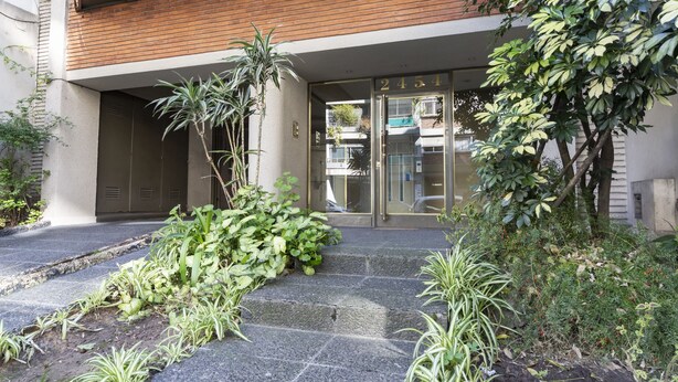 A building entrance with a glass door, a wooden overhang, and a stone pathway leading to the entrance. - Humboldt 2 by Be Local Argentina (Buenos Aires)