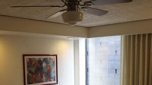A hotel room with a bed, a nightstand, a ceiling fan, a window with curtains, and a painting on the wall. - Hotel Manalba (Mexico City)