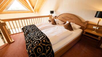 A bedroom with a wooden bed, a skylight, a nightstand with a lamp, and a wooden railing.