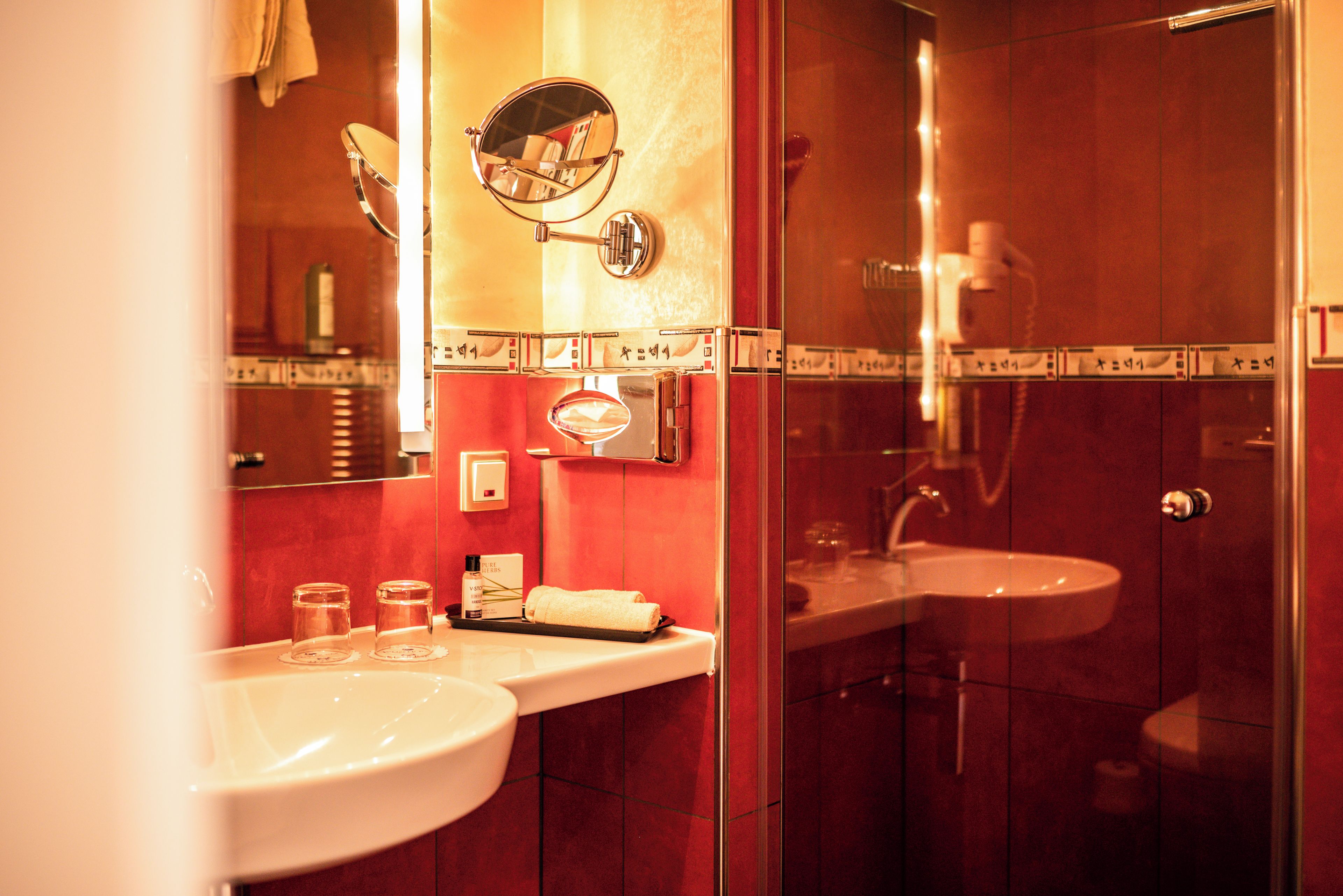 A bathroom with a glass shower enclosure, a sink, and a mirror.