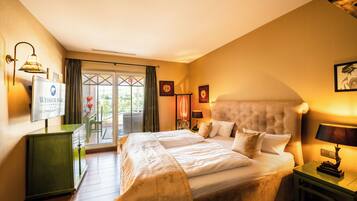 A hotel room with a large bed, a green cabinet, a desk, and a view of the outdoors through a glass door.