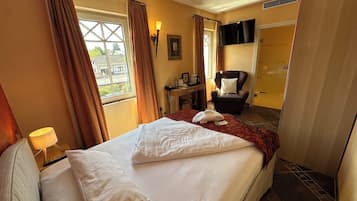A hotel room with a large bed, a chair, a desk with a lamp, and a view of the outside.