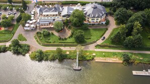 An aerial view of a lakeside property with a large house, a fountain, and a dock. - Wellness- & Genusshotel Weisser Bär (Muelheim)