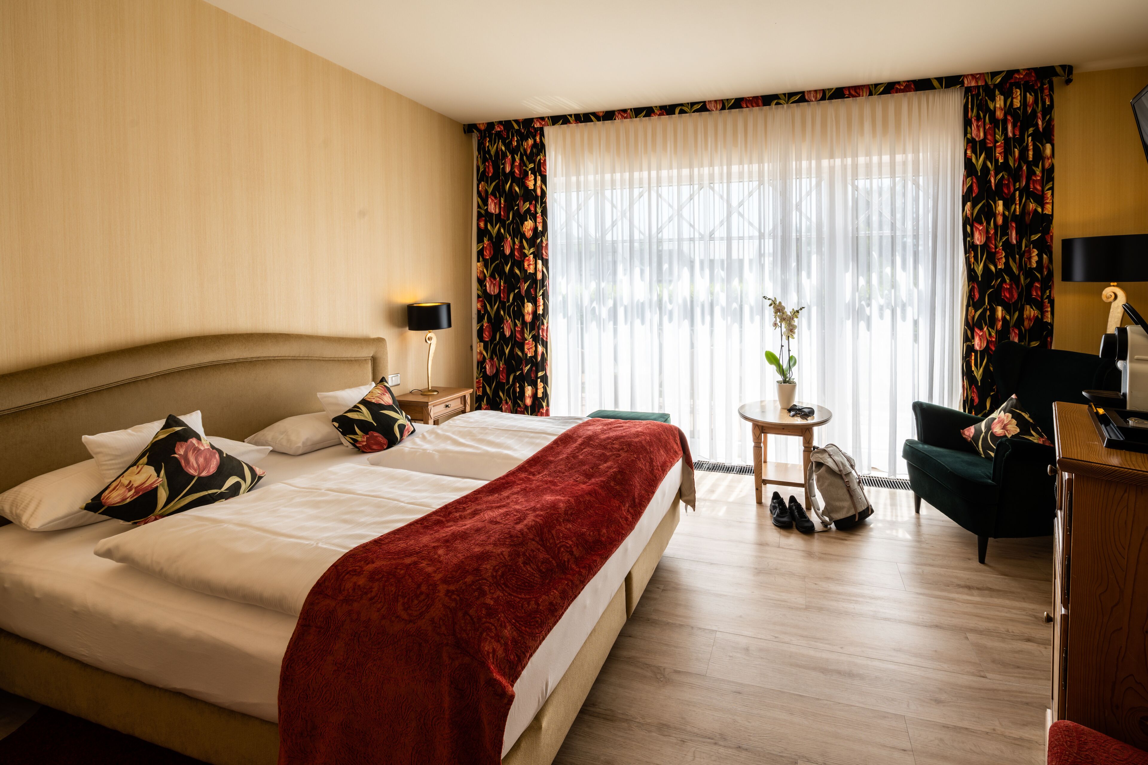Una camera d'albergo con un letto grande, una scrivania, una sedia e una finestra con tende.