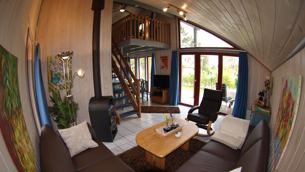 A cozy living room with a sofa, a coffee table, and a fireplace. - Sunny Danish cottage44. de am See in the holiday park Mirow (Granzow)