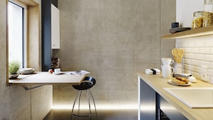 A modern kitchen with a concrete wall, wooden counter, and a window. - ipartment Cologne Mülheim (Cologne)