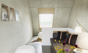 A modern interior with a concrete wall, a window, a sofa with cushions, a lamp, and a small table with flowers. - ipartment Cologne Mülheim (Cologne)