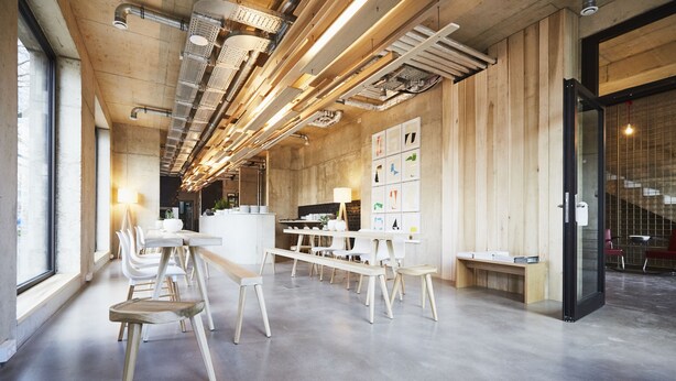 A modern office space with a long table, white chairs, and a wooden bench. - ipartment Cologne Mülheim (Cologne)