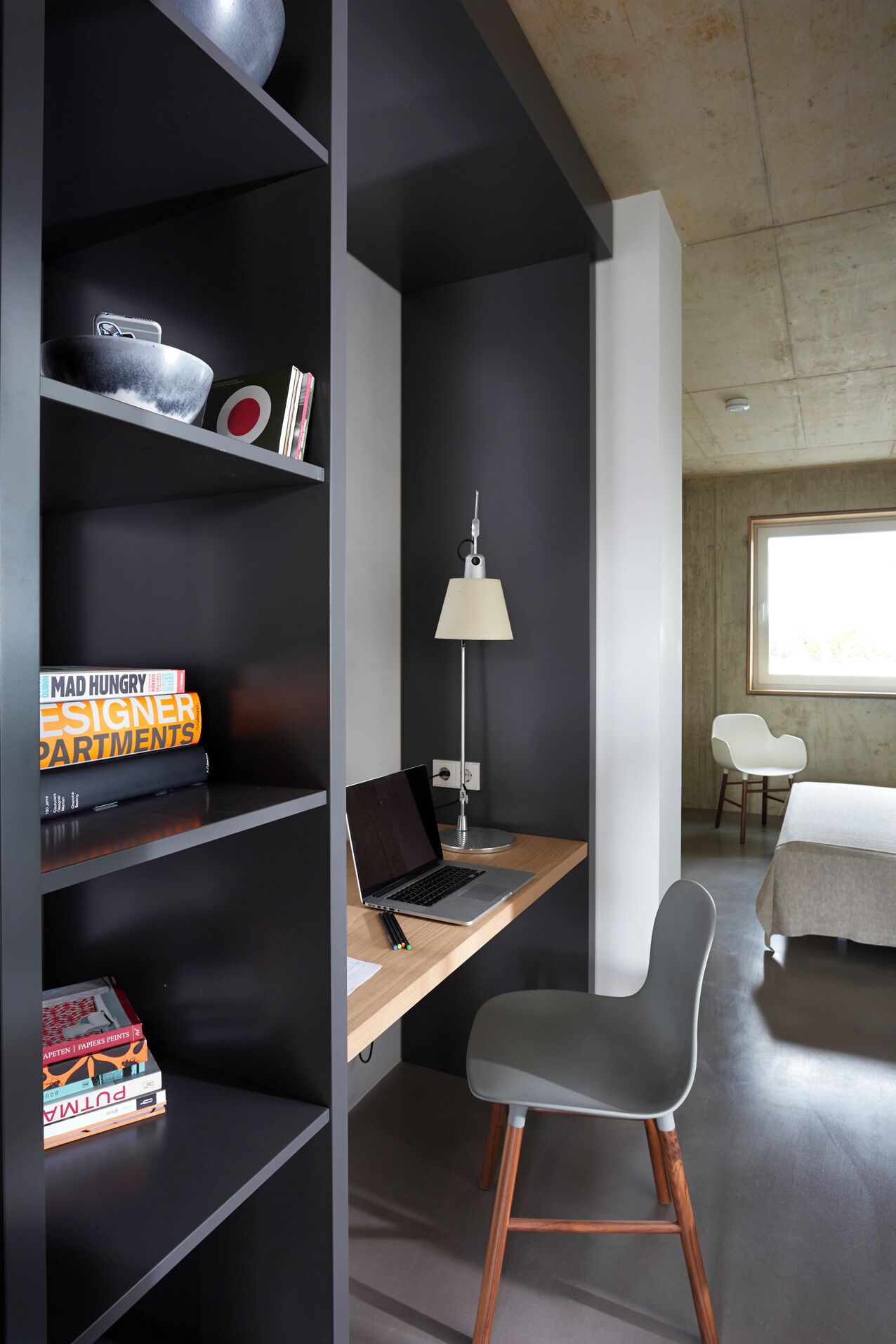 A modern bedroom with a desk, chair, and bookshelves.