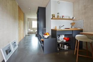 A modern kitchen with a grey countertop, white tiles, and wooden accents. - ipartment Cologne Mülheim (Cologne)