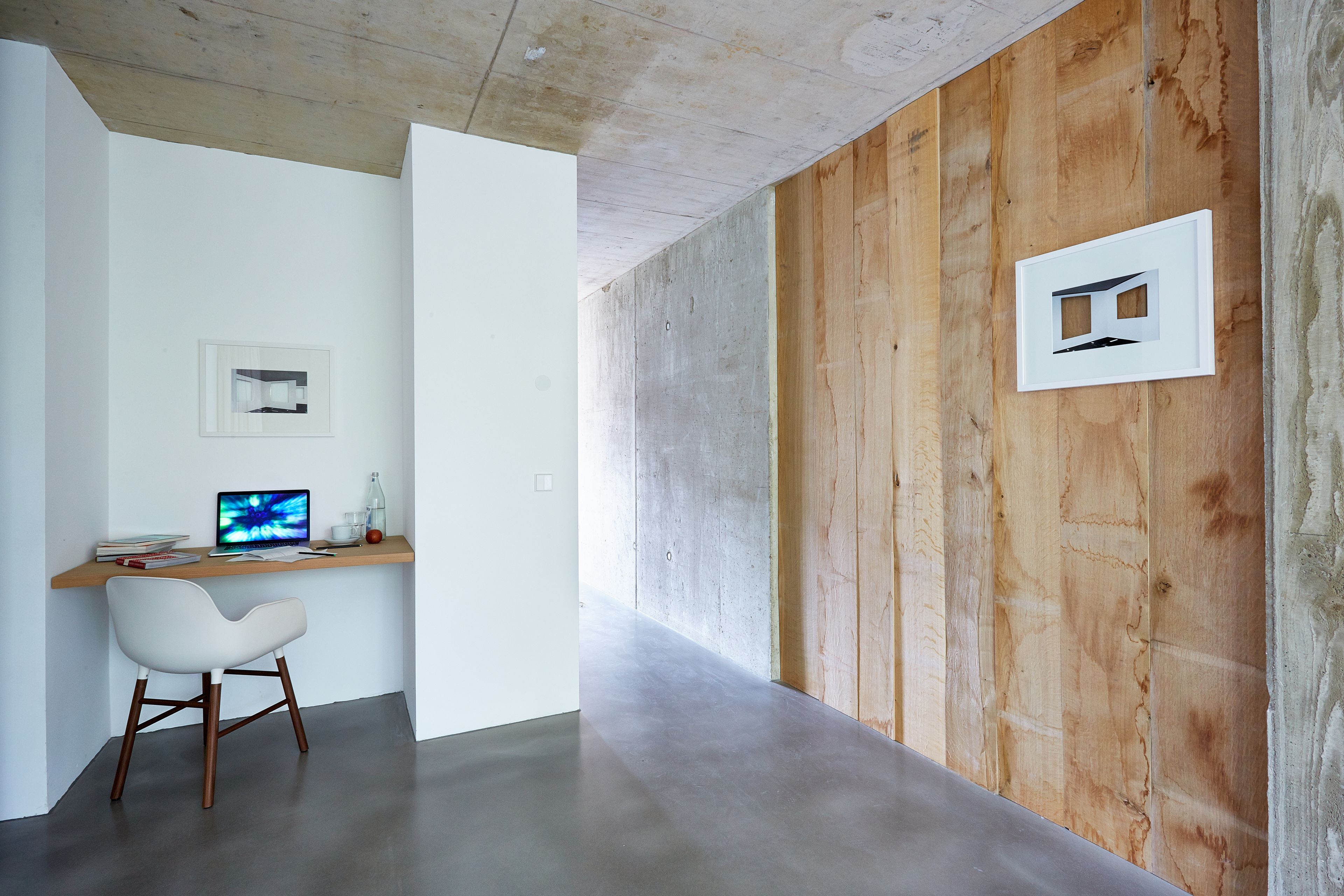 A modern office space with a wooden accent wall, a white desk, a computer, and a white chair.