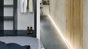 A modern bedroom with a built-in wardrobe, a bed, and a small kitchenette in the background. - ipartment Cologne Mülheim (Cologne)