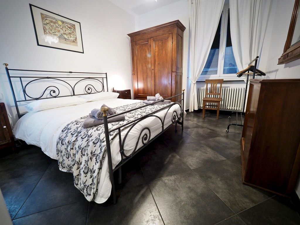 Ein Schlafzimmer mit Bett, einem Holzschrank, einem Heizkörper und einem Fenster mit Vorhängen.
