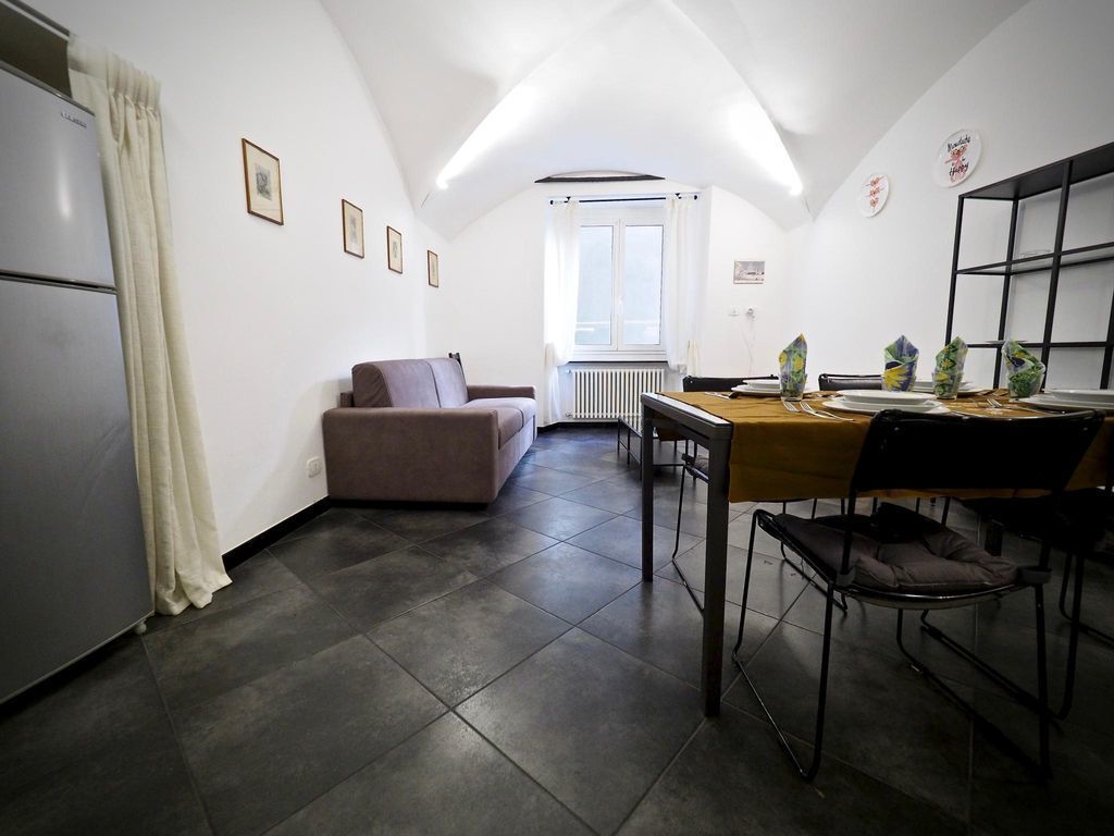 A compact kitchen with a dining area, a sofa, and a radiator.