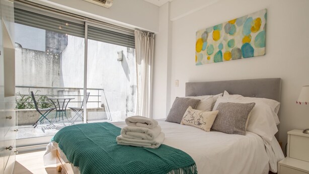 A bedroom with a bed, a green throw blanket, and a painting on the wall. - Las Heras by Be Local Argentina (Buenos Aires)
