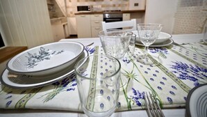 Ein Esstisch gedeckt mit Tellern, Gläsern und Besteck, mit einer blumigen Tischdecke.
