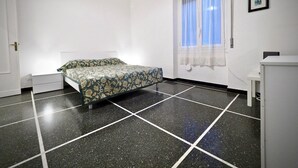 Ein Zimmer mit einem Bett, einem Vorhangfenster, einer weißen Tür und einem kleinen Tisch.