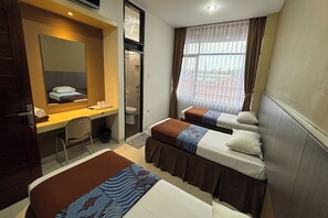 Ein Hotelzimmer mit zwei Betten, einem Schreibtisch, einem Stuhl, einem Spiegel und einem Fenster mit Vorhängen.
