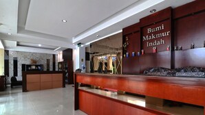 Un comptoir d’accueil avec une pancarte indiquant : « Bumi Makmur Indah ».