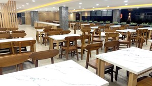 Un restaurant spacieux avec des tables et des chaises en bois, un comptoir et une vue sur l’extérieur.