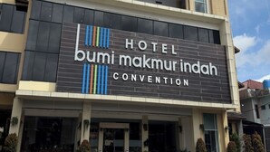 Un bâtiment d’hôtel avec une enseigne indiquant : « HÔTEL bumi makmur indah, CENTRE DE CONGRÈS ».