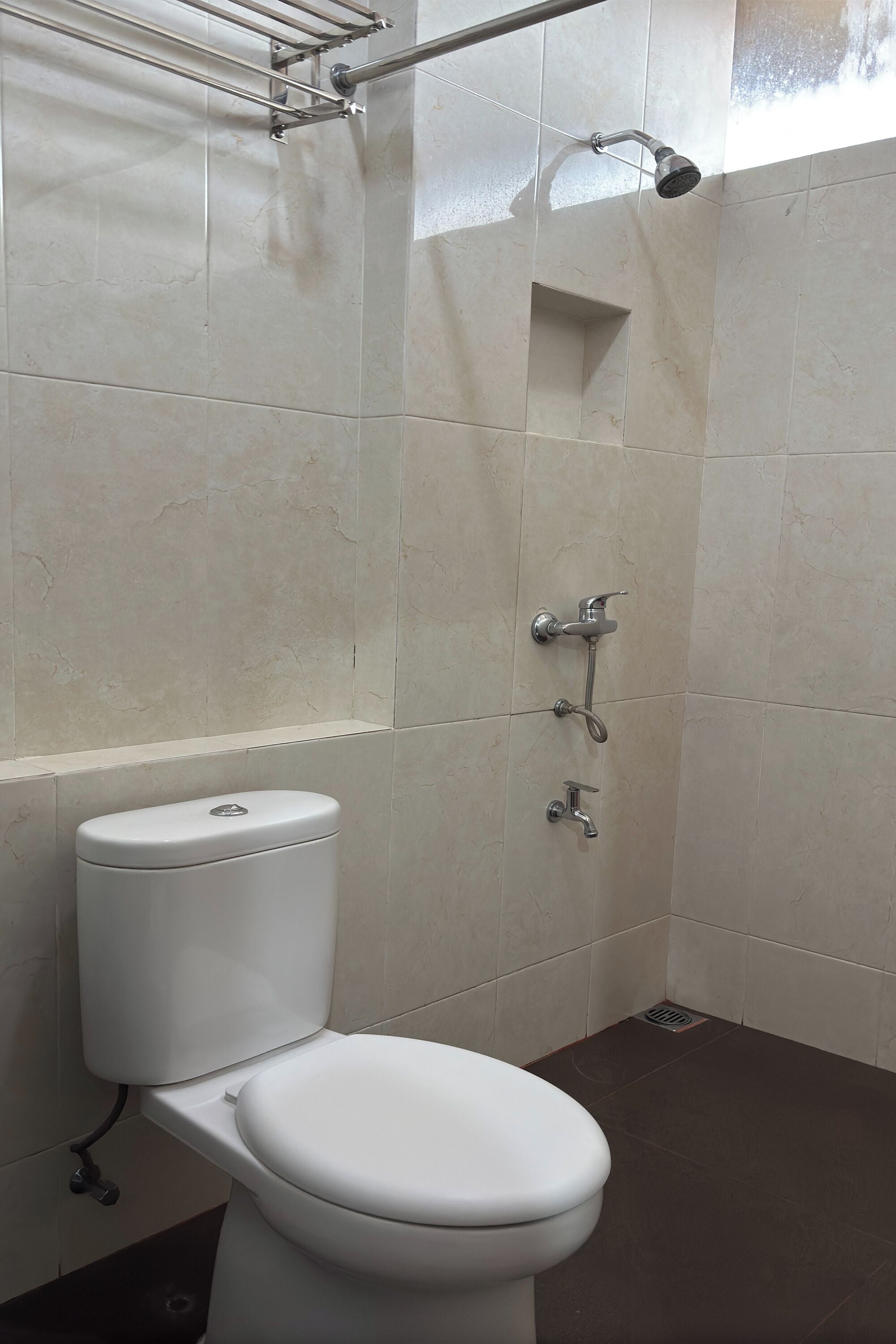A bathroom with a toilet, a shower with a handheld showerhead, and a towel rack.