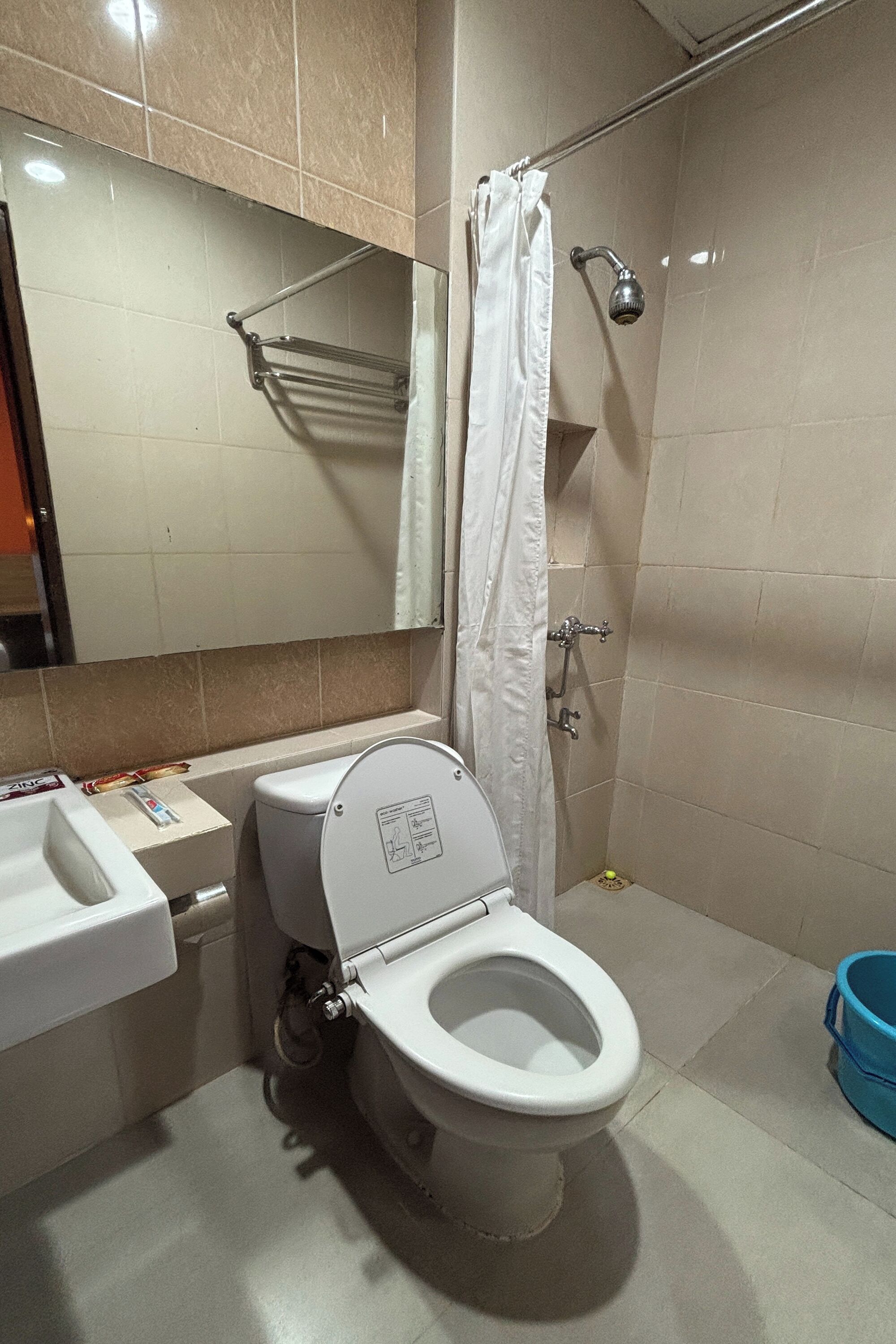 A bathroom with a toilet, sink, shower, and a towel rack.