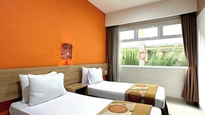 Une chambre d’hôtel avec deux lits, une grande fenêtre donnant sur un paysage verdoyant et une lampe fixée au mur.