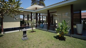 Un espacio al aire libre cubierto con un pequeño jardín, que incluye un farol de piedra, plantas en macetas y una estructura de pérgola.