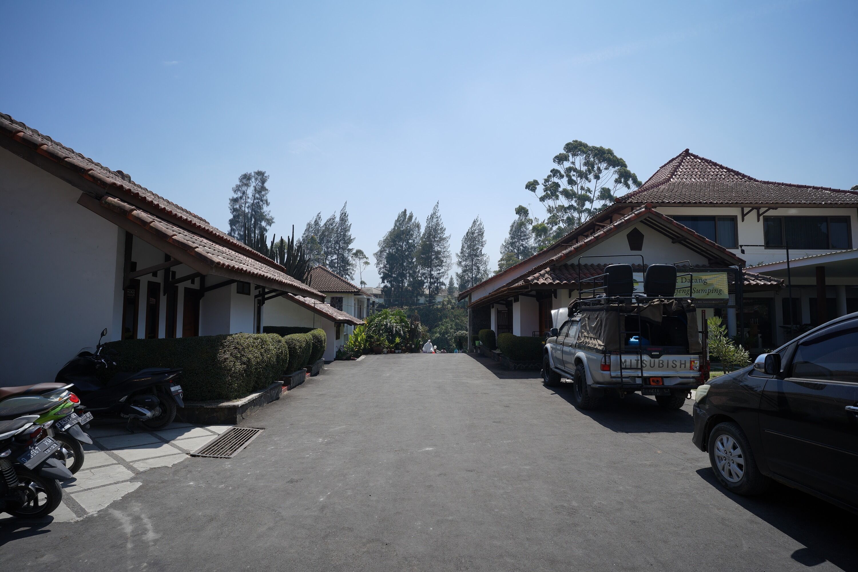 A street view with parked cars and a Mitsubishi truck.