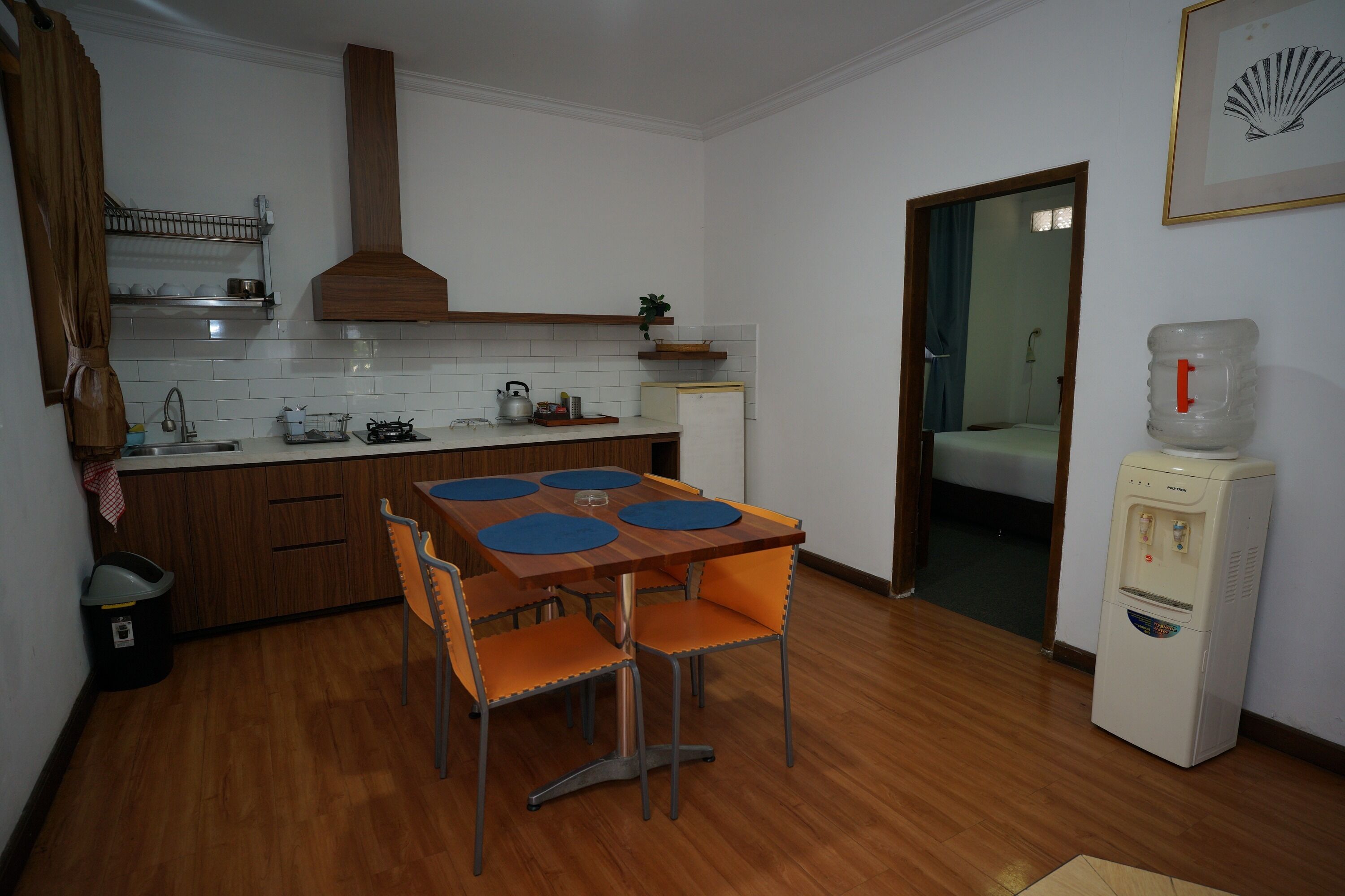Una cocina compacta con mesa, sillas, dispensador de agua y un refrigerador pequeño.