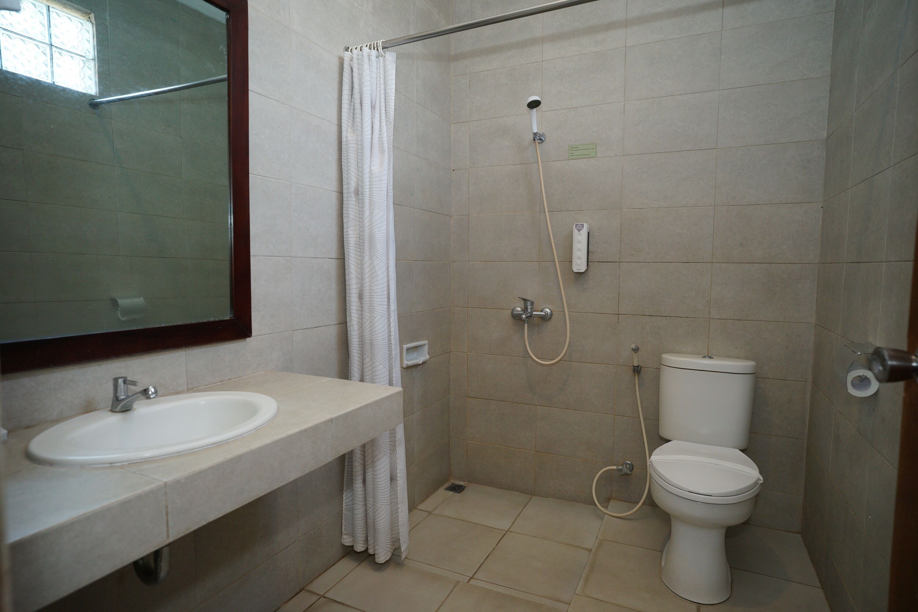 Une salle de bain équipée d’un lavabo, de toilettes, d’une douche et d’un miroir.
